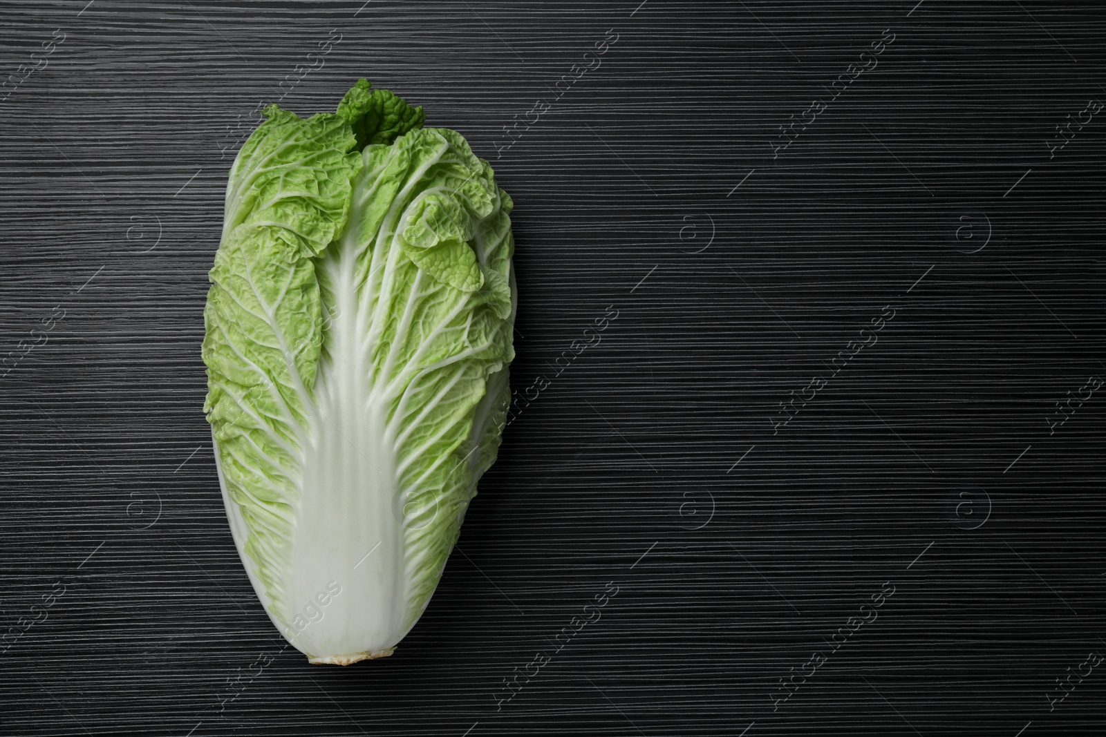 Photo of Fresh ripe Chinese cabbage on black wooden table, top view. Space for text