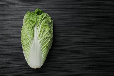 Fresh ripe Chinese cabbage on black wooden table, top view. Space for text