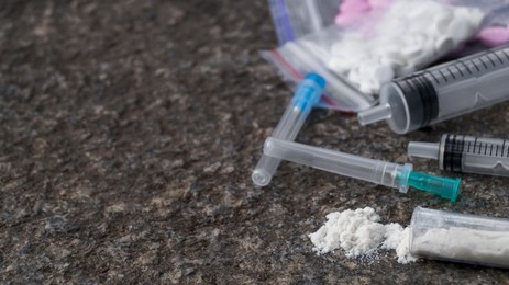 Pills, syringes and powder on stone surface, closeup with space for text. Hard drugs