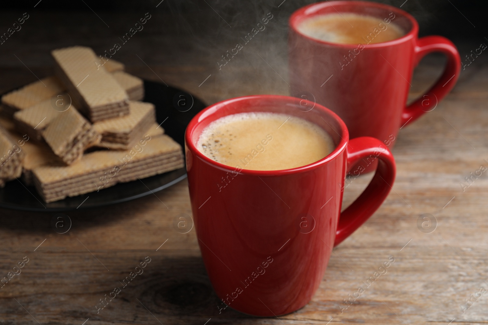 Photo of Delicious coffee and wafers on wooden table