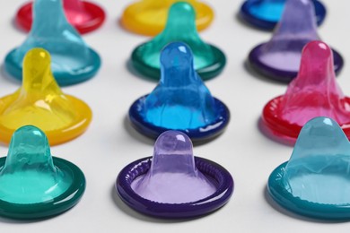 Photo of Colorful condoms on white background, closeup. Safe sex