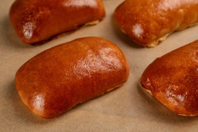 Photo of Delicious baked pirozhki on parchment paper, closeup