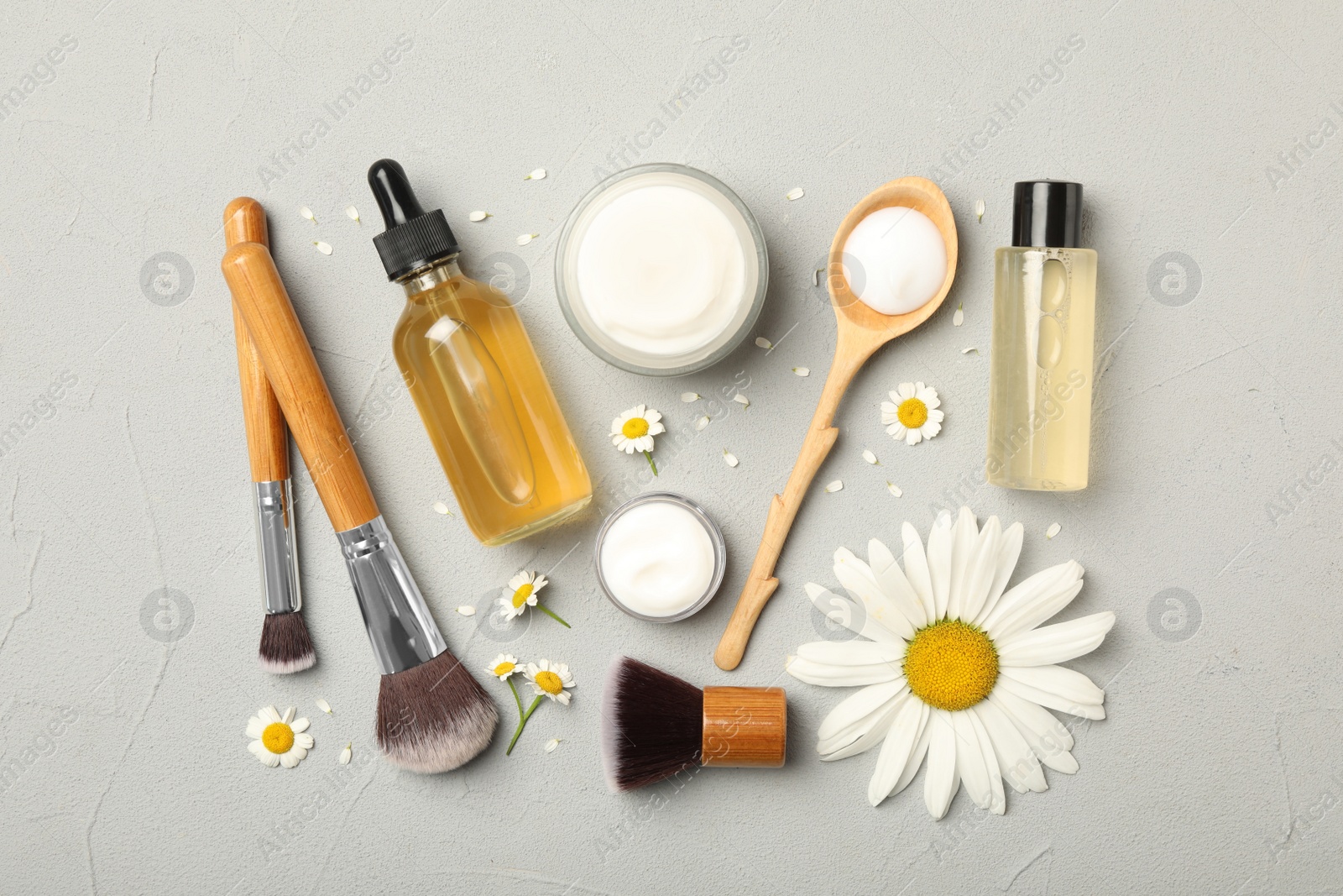 Photo of Flat lay composition with chamomiles, beauty accessories and cosmetic products on grey background