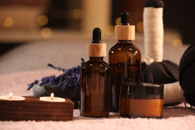 Composition with spa products and burning candles on soft light surface, closeup