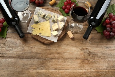 Photo of Tasty red wine and snacks on wooden table, flat lay. Space for text