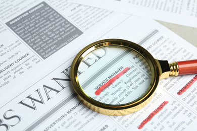 Magnifying glass on newspaper. Job search concept