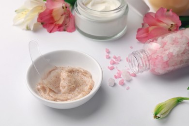 Bowl of scrub and sea salt on white table, closeup. Spa composition