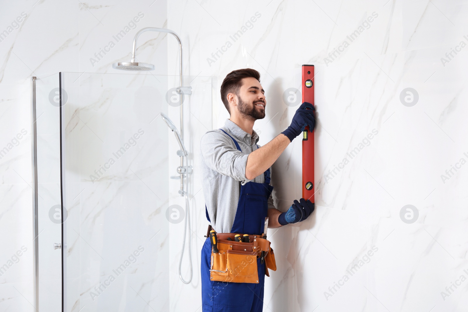 Photo of Handyman working with building level in bathroom. Professional construction tools