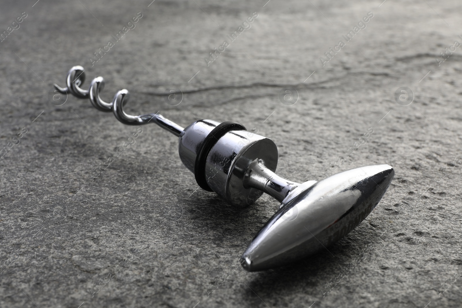 Photo of One metal corkscrew on grey textured table, closeup