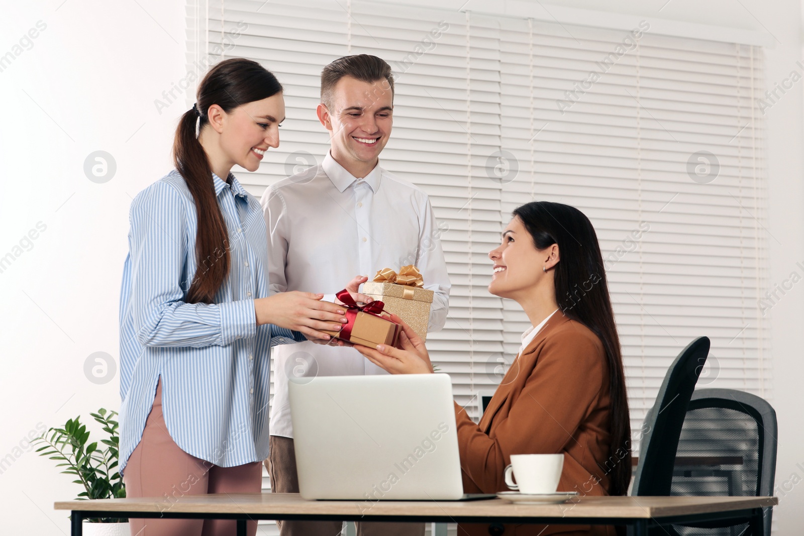 Photo of Colleagues presenting gifts to woman in office