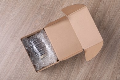 Jar with bubble wrap in cardboard box on wooden table, top view