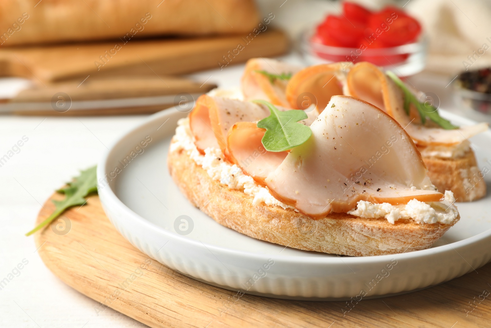 Photo of Board with plate of delicious chicken bruschettas on table, closeup