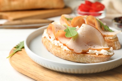 Photo of Board with plate of delicious chicken bruschettas on table, closeup