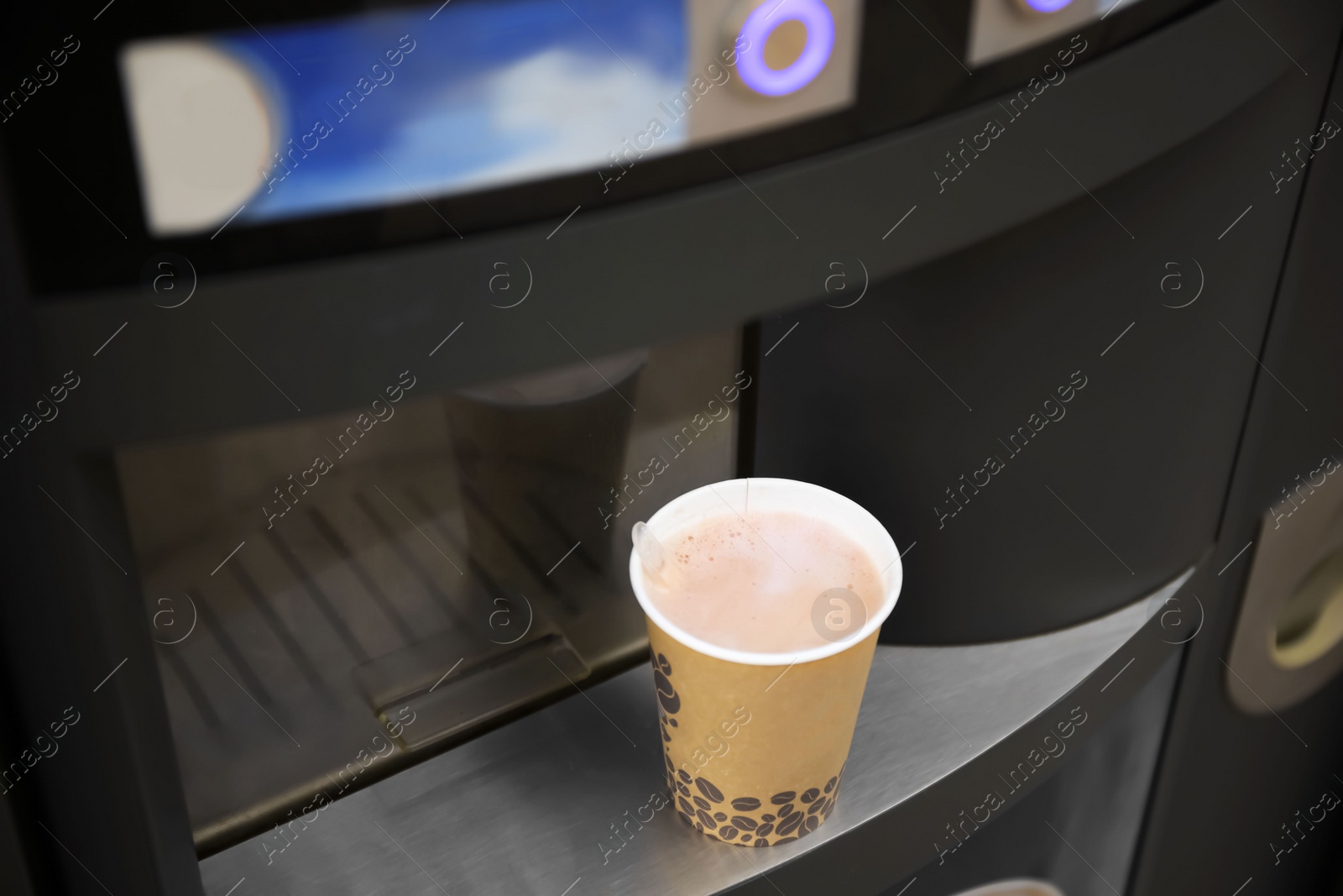 Photo of Coffee and hot beverage vending machine with paper cup on drip tray, above view