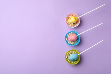 Photo of Egg shaped cake pops and space for text on violet background, flat lay. Easter celebration