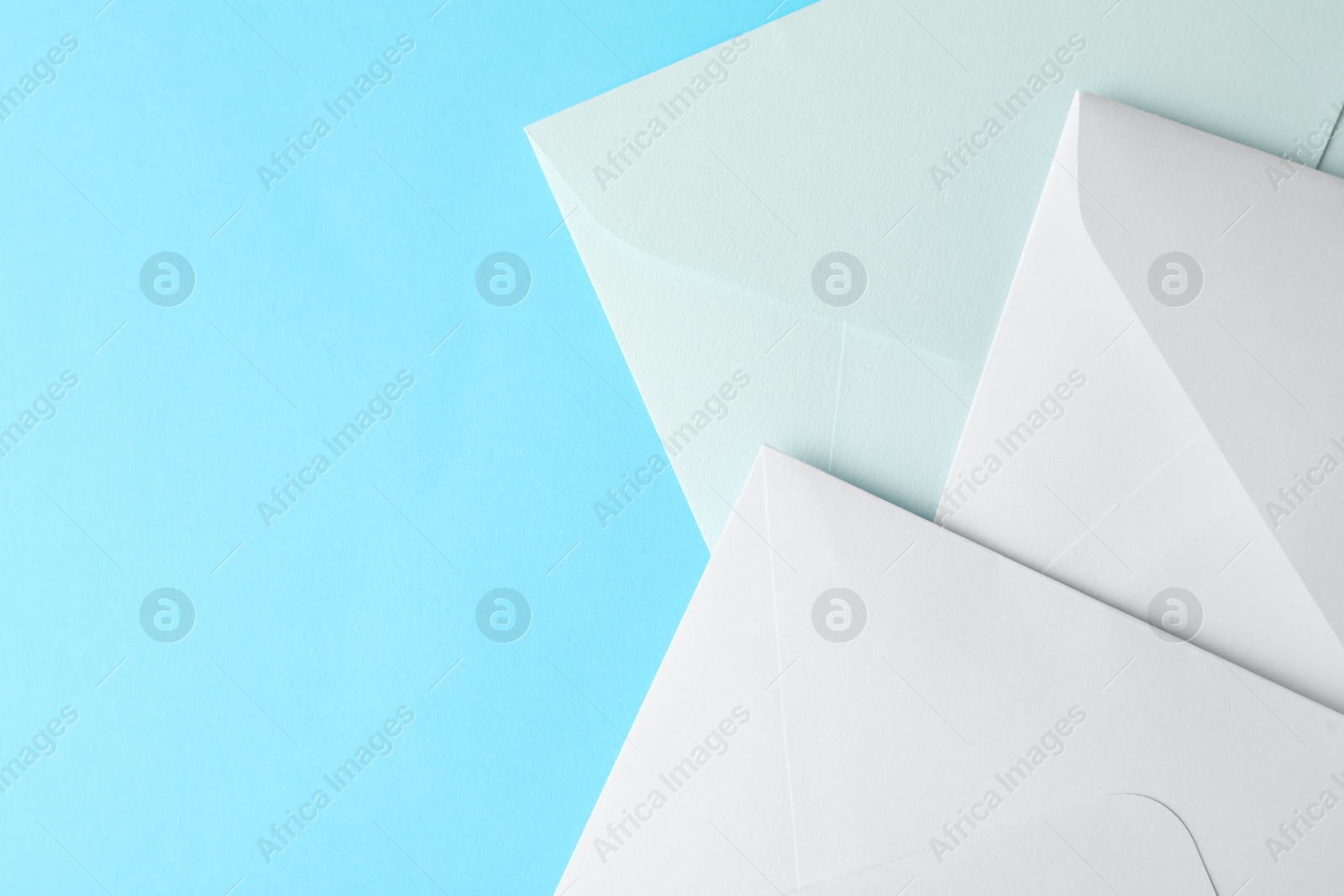 Photo of White paper envelopes on light blue background, flat lay. Space for text