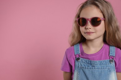 Photo of Girl in stylish sunglasses on pink background, space for text