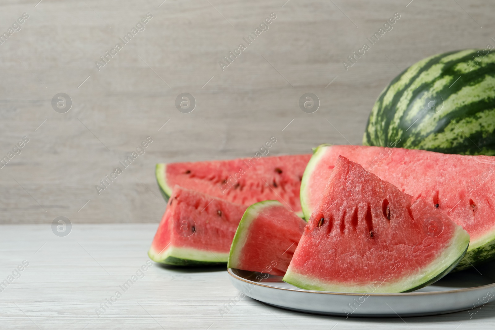 Photo of Tasty ripe watermelons on white wooden table, space for text