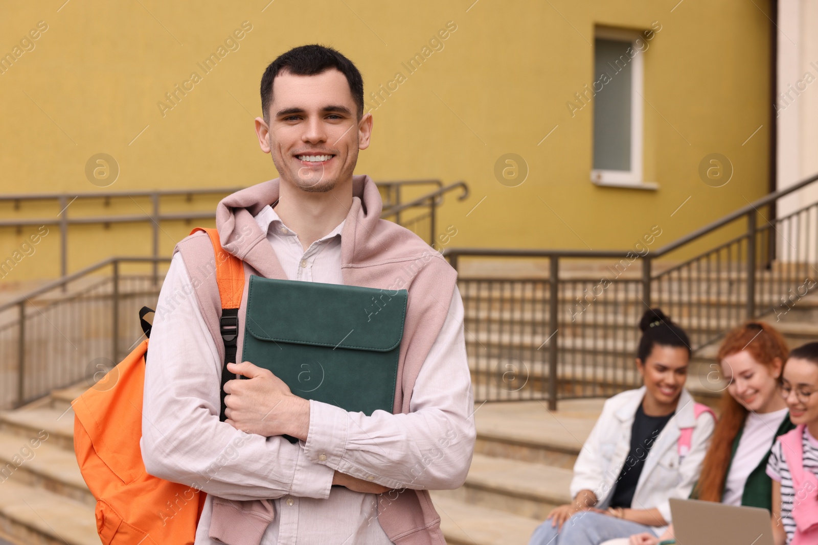 Photo of Students learning together on steps. Happy young man with tablet outdoors, selective focus