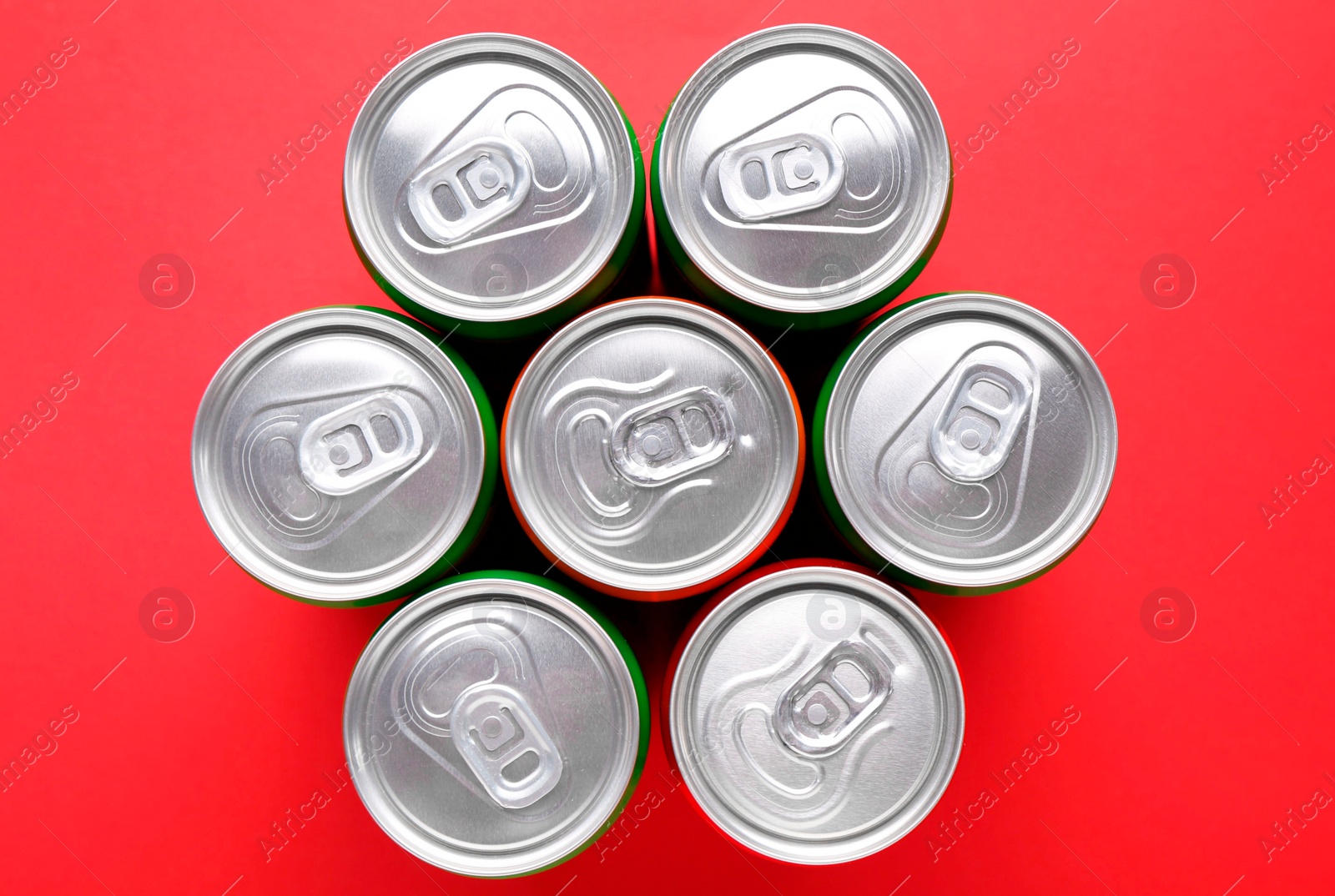 Photo of Energy drink in cans on red background, top view