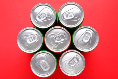 Photo of Energy drink in cans on red background, top view
