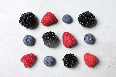 Photo of Many different fresh ripe berries on white textured table, flat lay