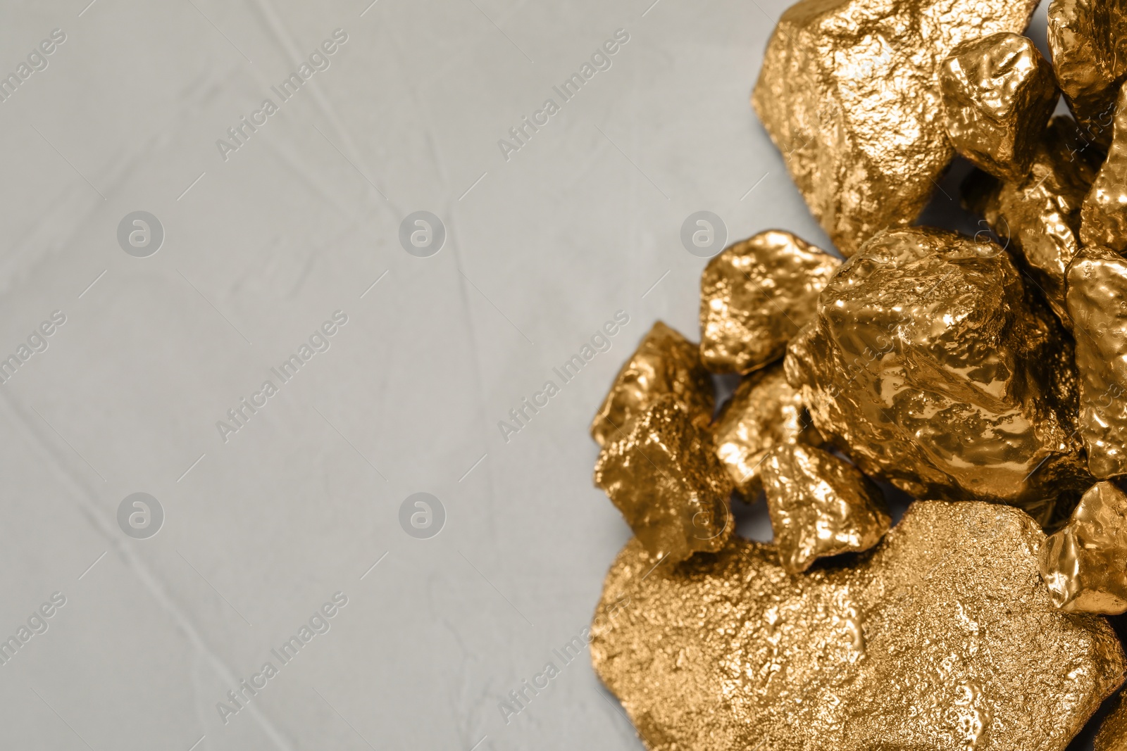 Photo of Pile of gold nuggets on light grey table, flat lay. Space for text