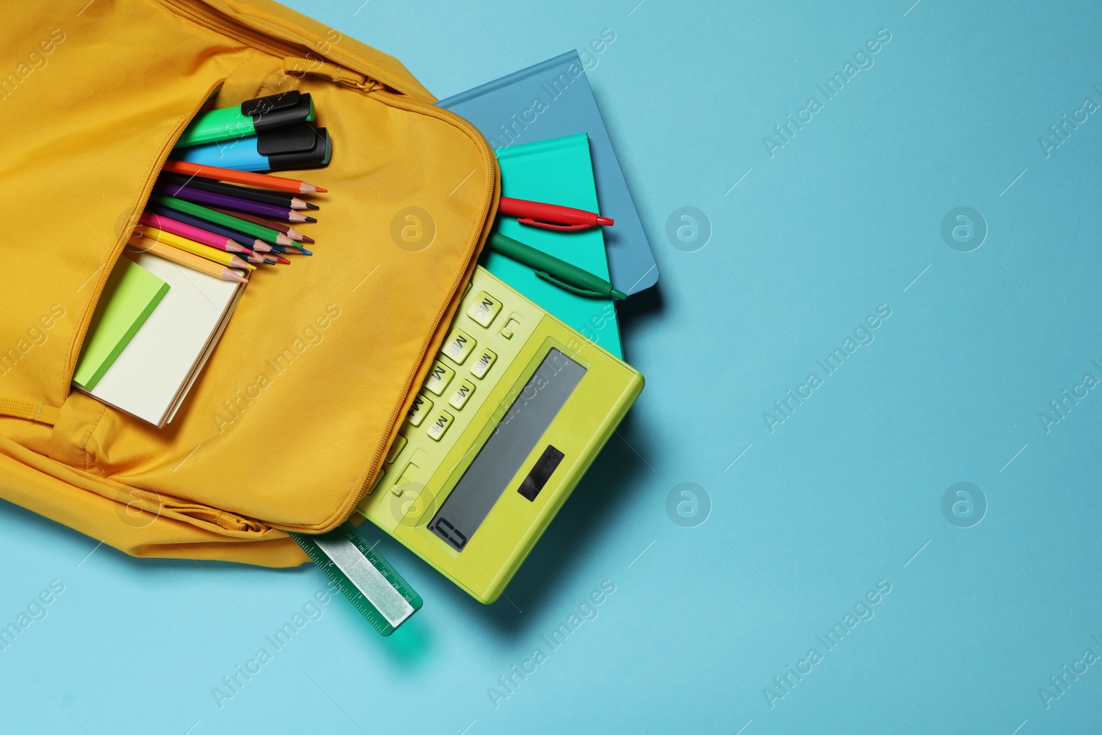 Photo of Backpack with different school stationery on light blue background, top view. Space for text