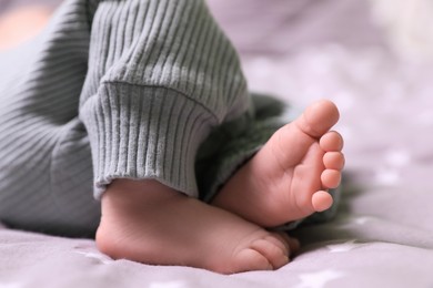 Cute newborn baby lying on bed, closeup of legs