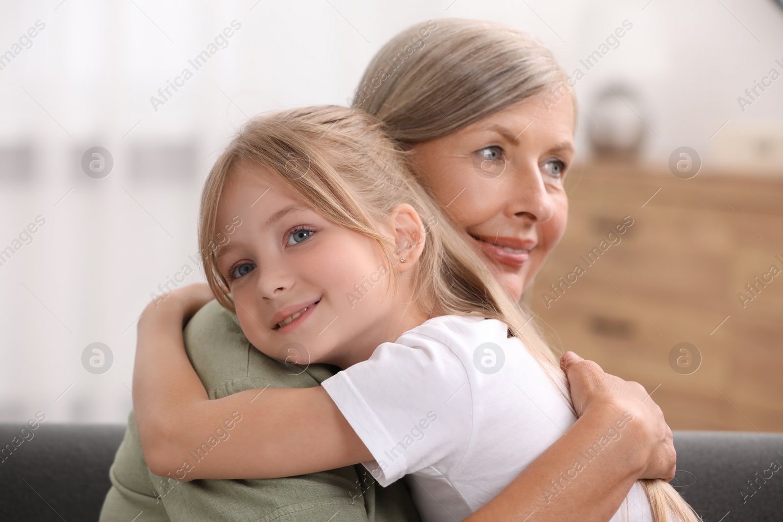 Photo of Happy grandmother hugging her granddaughter at home