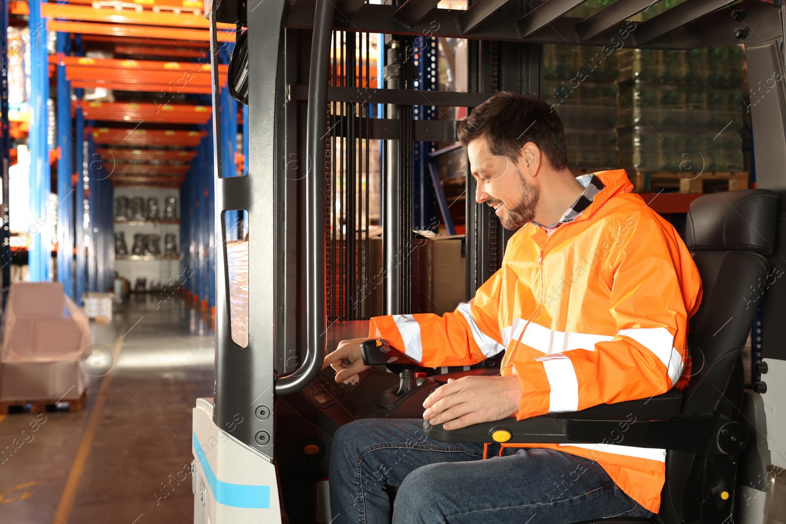 Photo of Happy worker sitting in forklift truck at warehouse