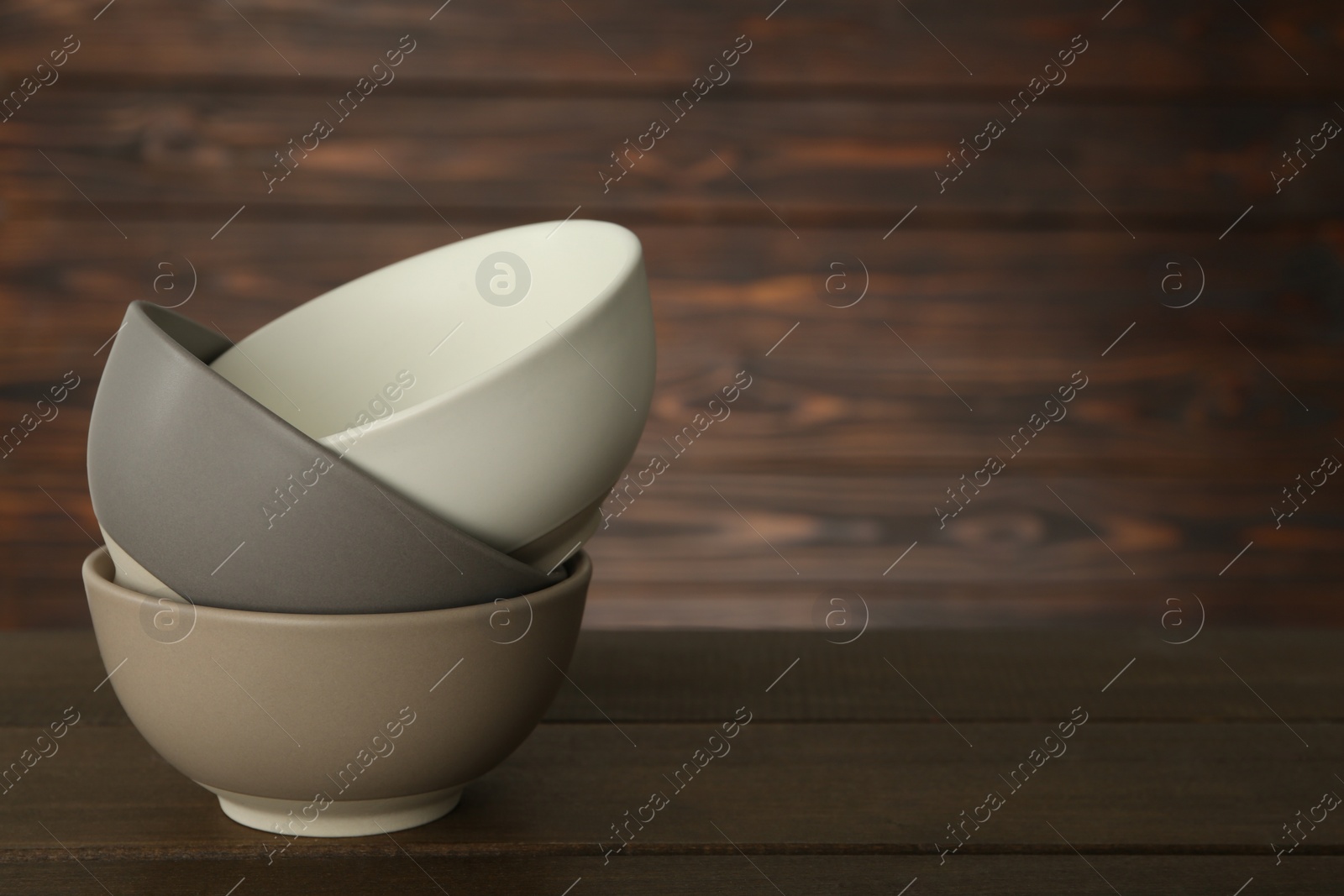 Photo of Stylish empty ceramic bowls on wooden table, space for text. Cooking utensils