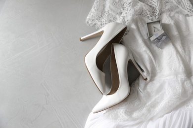 Photo of Wedding dress, white high heel shoes and ring on grey background, flat lay. Space for text