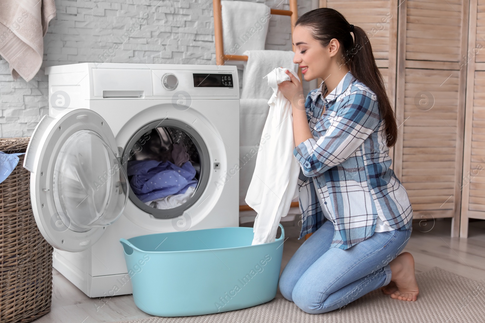 Photo of Young woman doing laundry at home