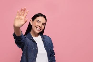 Photo of Happy woman giving high five on pink background, space for text
