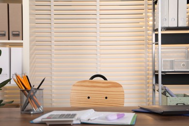 Photo of Stylish office interior with wooden desk, shelving units and stationery