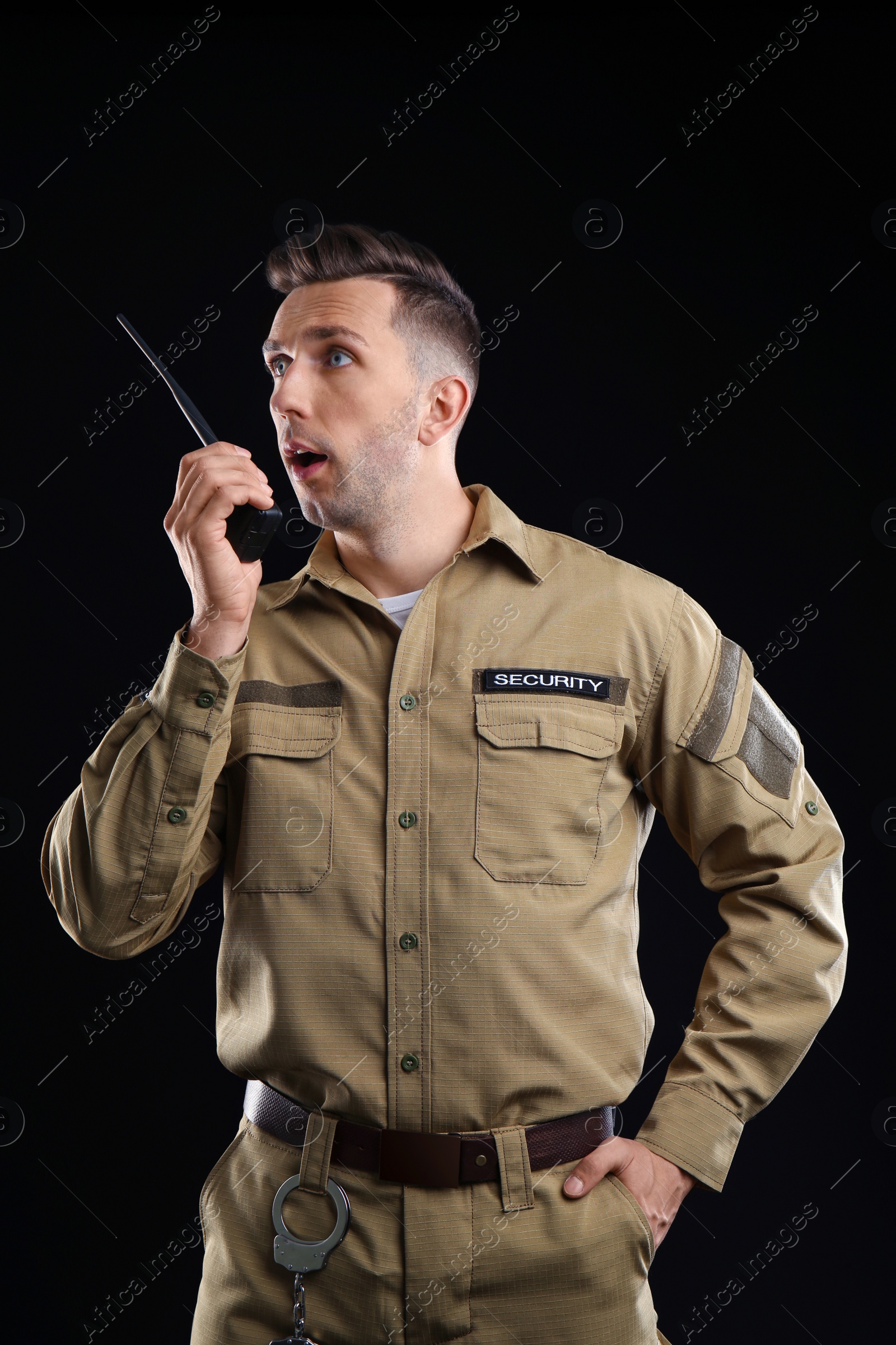 Photo of Male security guard using portable radio transmitter on dark background