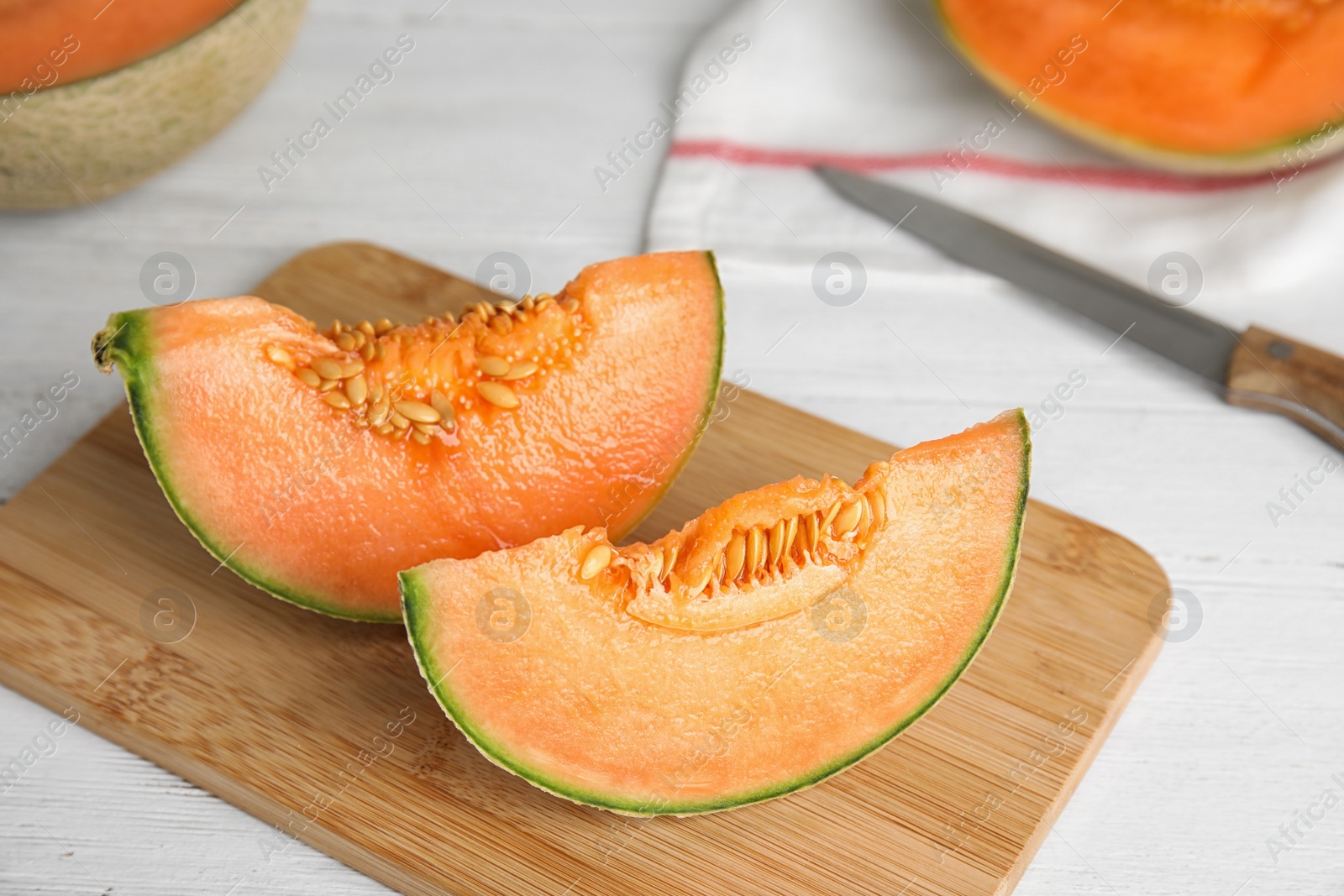 Photo of Slices of ripe cantaloupe melon on white wooden table