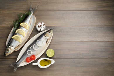 Photo of Delicious salted herrings and ingredients on wooden table, flat lay. Space for text
