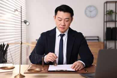 Notary stamping document at wooden table in office