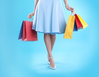 Photo of Young woman with shopping bags on color background, closeup of legs