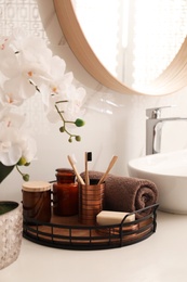 Photo of Beautiful flowers and different toiletries near vessel sink in bathroom