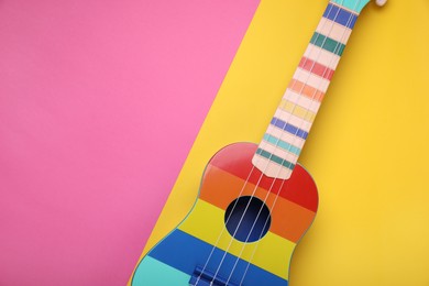 Photo of Bright ukulele on color background, top view and space for text. String musical instrument