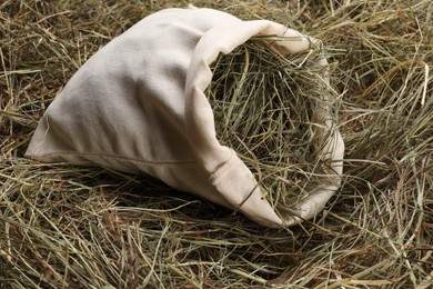 Dried hay in burlap sack on table, closeup