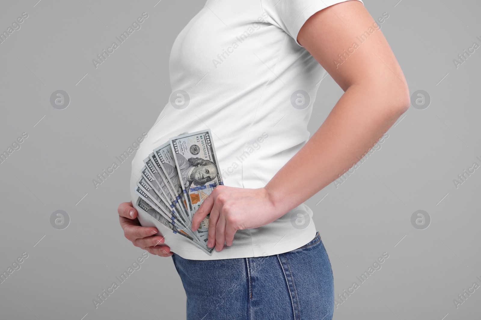 Photo of Surrogate mother. Pregnant woman with dollar banknotes on light grey background, closeup