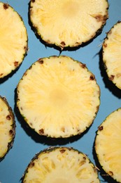 Slices of tasty ripe pineapple on light blue background, flat lay