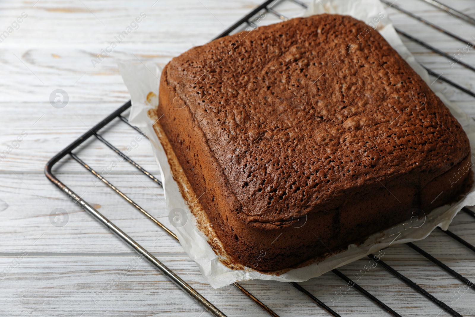 Photo of Homemade chocolate sponge cake on white wooden table, closeup. Space for text