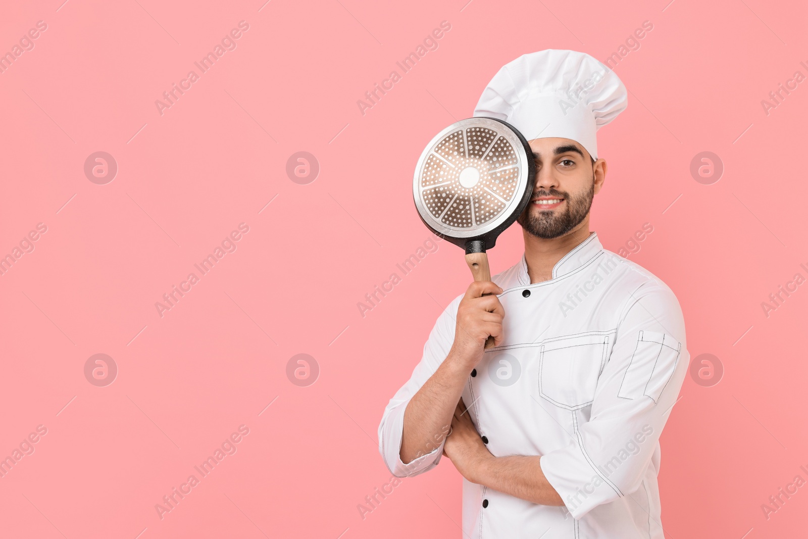 Photo of Professional chef with frying pan on pink background. Space for text