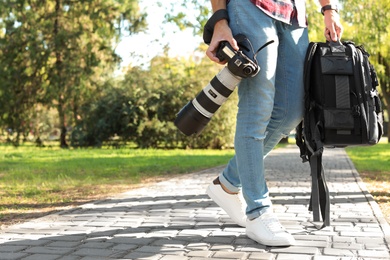 Photo of Young male photographer with professional camera and backpack in park. Space for text