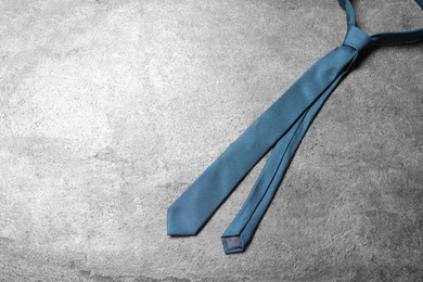 Photo of One blue necktie on grey textured background, top view. Space for text